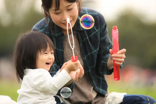 アジア系の母親と子供がシャボン玉で遊んでいて — ストック写真