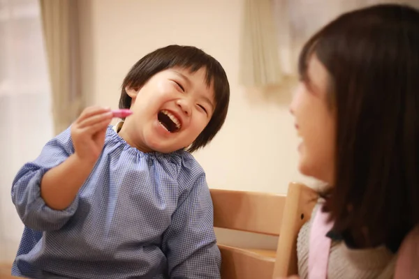 Annesiyle birlikte çizen yakışıklı Asyalı çocuk.