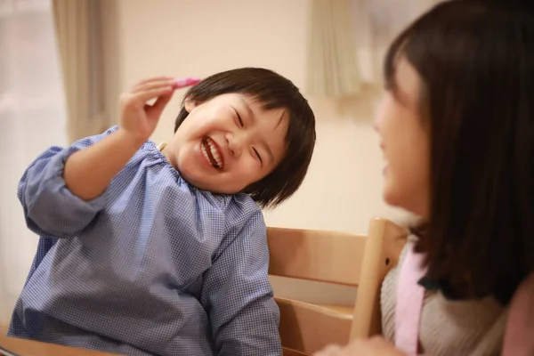 Annesiyle birlikte çizen yakışıklı Asyalı çocuk.