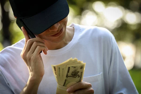Mladý Asijský Muž Drží Peníze Mluví Smartphone — Stock fotografie
