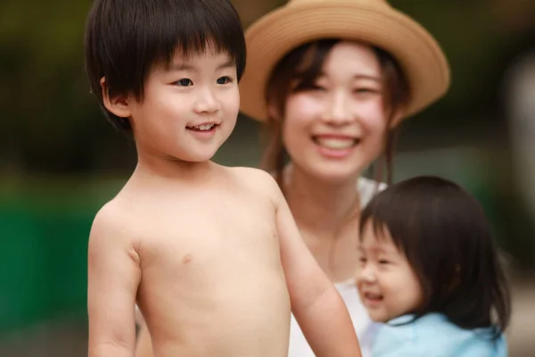 夏には娘と息子と帽子をかぶった若いアジア系の母親が — ストック写真