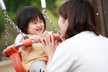 Parkta oynayan Asyalı aile.