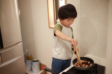 Asyalı çocuk mutfakta yemek hazırlıyor.