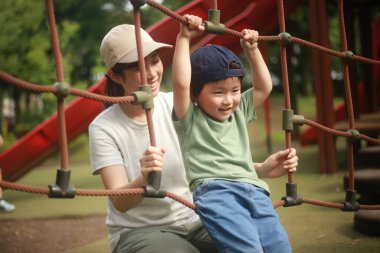 Mutlu çocuk parkta oyun parkına tırmanıyor.