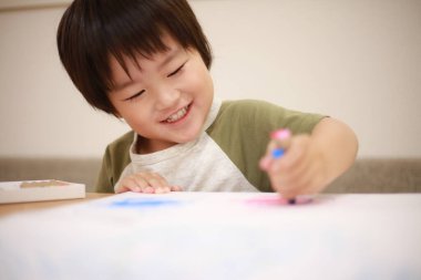 Asyalı küçük çocuk resim yapıyor.