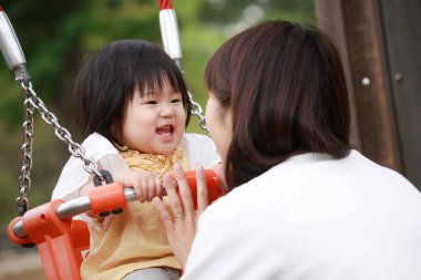 Parkta oynayan Asyalı aile.