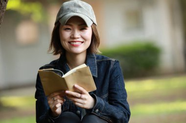 Açık havada kitap okuyan öğrenci kadın. 