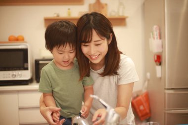 Anne oğluna el yıkamayı öğretiyor.