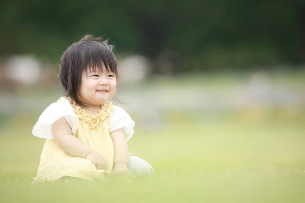 Aasian Tyttö Istuu Vihreällä Ruoholla — kuvapankkivalokuva