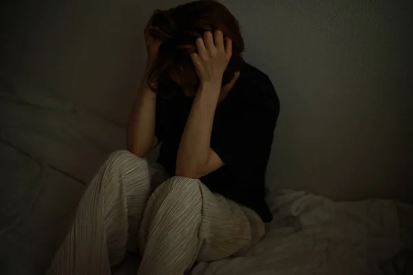 部屋のベッドに座っているパジャマ姿の悲しい女性 — ストック写真