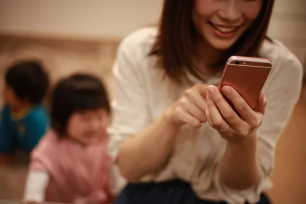 Giovane Madre Asiatica Utilizzando Smartphone Bambini Sullo Sfondo — Foto Stock