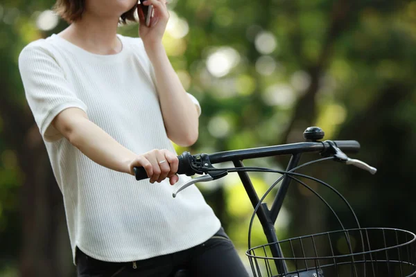 亚洲女孩骑自行车 手持智能手机 — 图库照片
