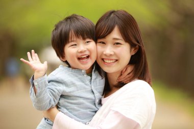 Genç Asyalı anne ve küçük oğlu parkta eğleniyorlar.  