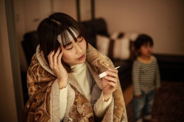 Asyalı kadın vücut ısısını dijital termometreyle kontrol ediyor