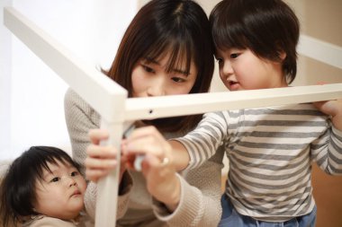 Çocuklu Asyalı kadın yeni evinde masa topluyor.