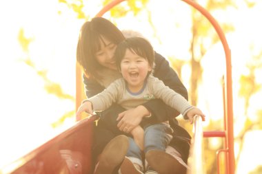 Küçük sevimli Asyalı çocuk ve annesi parkta.