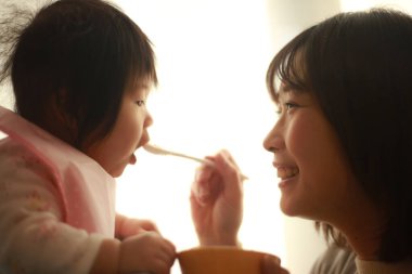 Genç anne, sevimli bebeği evde besliyor.