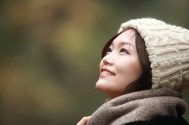 Sonbahar parkında poz veren Asyalı genç kadının portresi. 