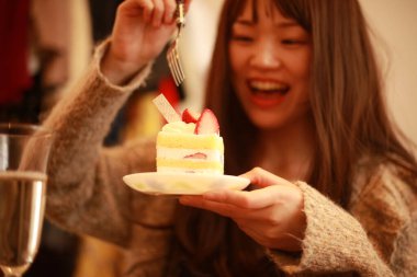 Genç Asyalı kadın pasta yiyor.