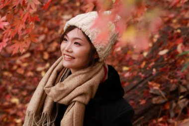 Sonbahar parkında poz veren Asyalı genç kadının portresi. 