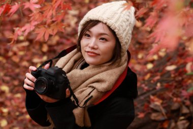 Sonbahar parkında resim çeken Asyalı genç bir kadının portresi. 