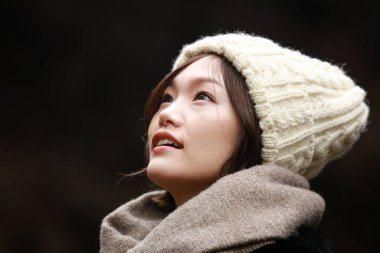 Sonbahar parkında poz veren Asyalı genç kadının portresi. 