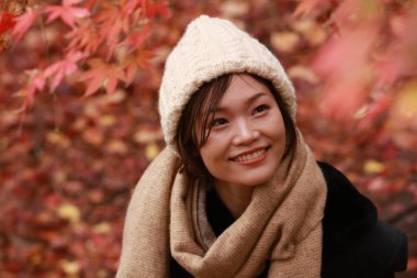 Sonbahar parkında poz veren Asyalı genç kadının portresi. 