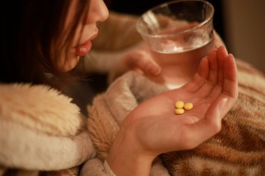 Soğuk algınlığı olan hasta bir kadın ilaç alıyor.