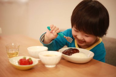 Küçük tatlı çocuk mutfakta yemek yiyor. 