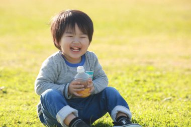 Parkta meyve suyu içen mutlu çocuk portresi