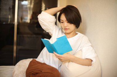 Kanepede kitap okuyan güzel bir kadın.