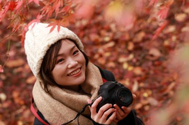 Sonbahar parkında resim çeken Asyalı genç bir kadının portresi. 