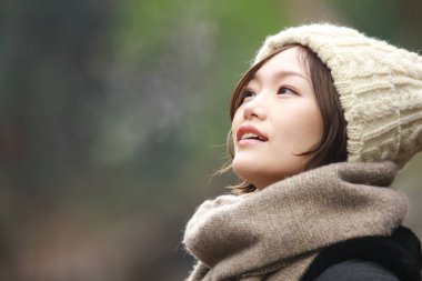 Sonbahar parkında poz veren Asyalı genç kadının portresi. 