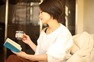 Kanepede kitap okuyan güzel bir kadın.