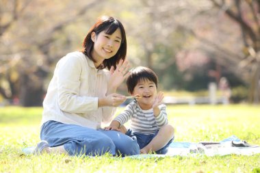 Asyalı anne oğluyla parkta yemek yiyor.