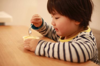 Asyalı şirin çocuk mutfakta yemek yiyor.