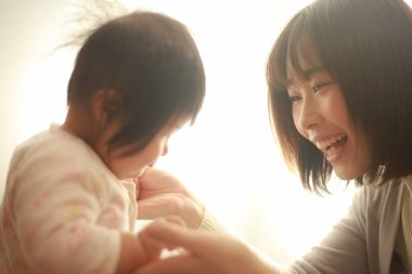 Güzel genç anne pencere ışığında kızıyla oynuyor.  