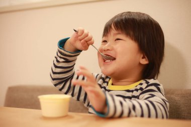 Asyalı şirin çocuk mutfakta yemek yiyor.