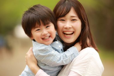 Genç Asyalı anne ve küçük oğlu parkta eğleniyorlar.  