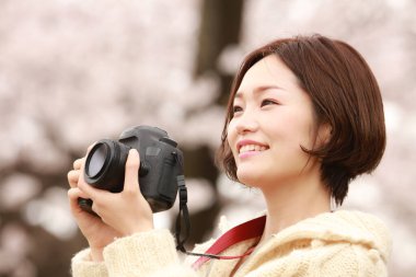 Parkta kamerası olan genç bir kadın.