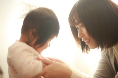 Güzel genç anne pencere ışığında kızıyla oynuyor.  