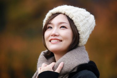 Sonbahar parkında poz veren Asyalı genç kadının portresi. 