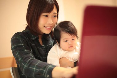 Kadın çocuğuyla birlikte evden çalışıyor.