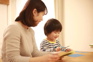 Gülümseyen Asyalı genç kadın ve küçük oğlu el kreması yapıyorlar. 