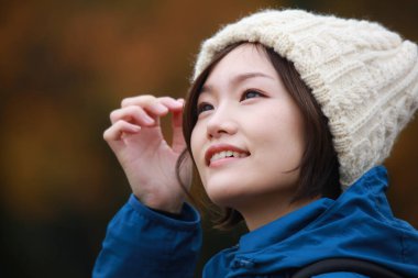 Sonbahar parkında poz veren Asyalı genç kadının portresi. 