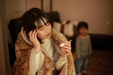 Asyalı kadın vücut ısısını dijital termometreyle kontrol ediyor