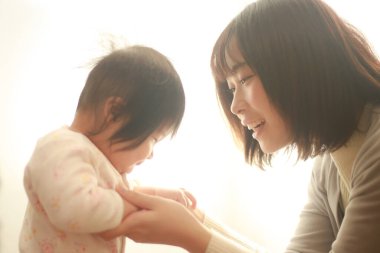 Güzel genç anne pencere ışığında kızıyla oynuyor.  