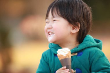 Çocuk parkta dondurma yiyor.