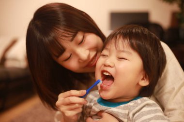 Genç anne, küçük oğlu için dişlerini fırçalıyor.
