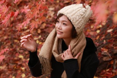 Sonbahar parkında poz veren Asyalı genç kadının portresi. 